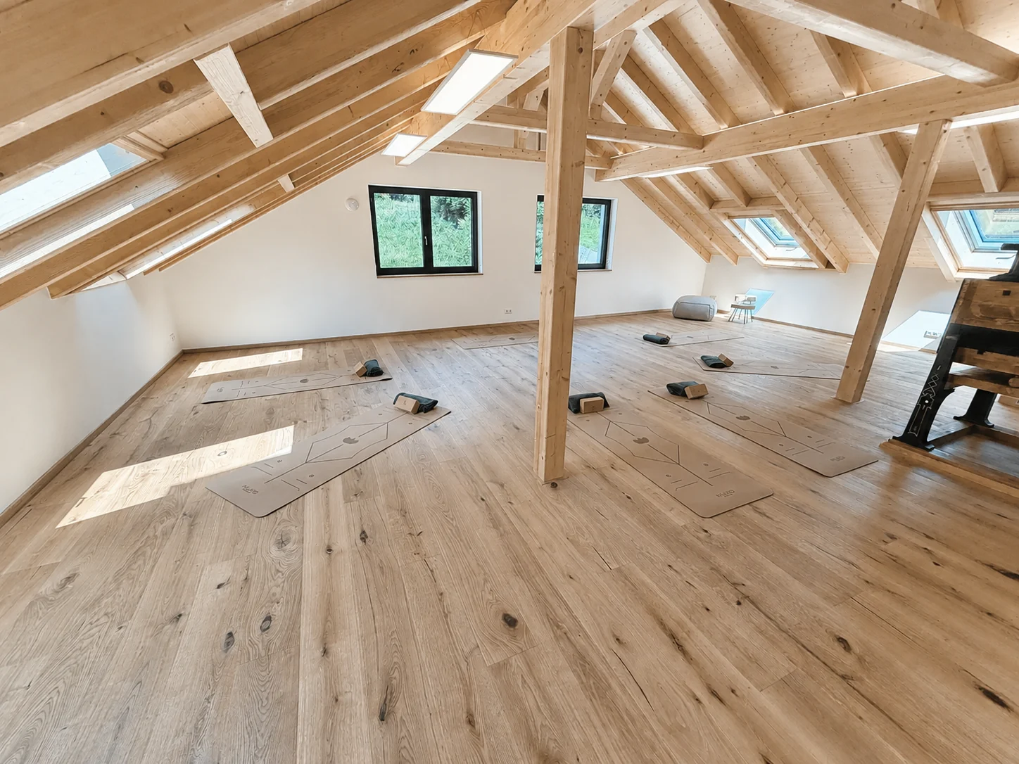 Weitläufiger Yogaraum unter sichtbaren Holzbalken